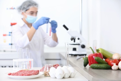Different food on table and scientist proceeding quality control in laboratory