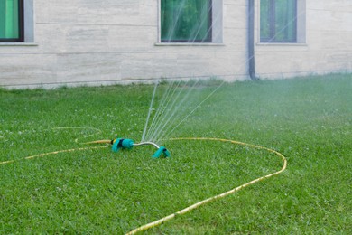 Automatic sprinkler watering green grass on lawn outdoors