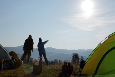 Couple enjoying beautiful mountain landscape near camping tents, back view
