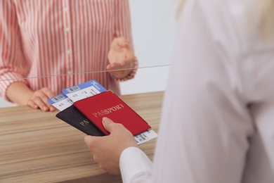 Agent giving passports with tickets to client at check-in desk in airport, closeup