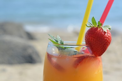 Glass of refreshing drink with strawberry and mint near sea, closeup. Space for text