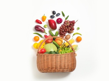 Basket with assortment of fresh organic fruits and vegetables on white background, top view