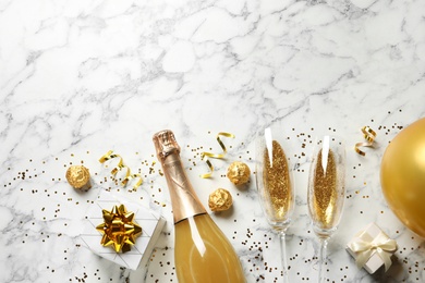 Flat lay composition with bottle of champagne for celebration on white marble background. Space for text