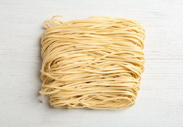 Block of quick cooking noodles on wooden background, top view