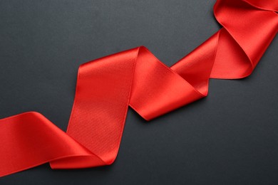 Beautiful red ribbon on black background, top view