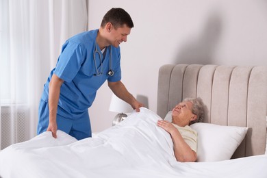 Caregiver assisting senior woman in bedroom. Home health care service