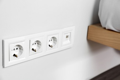 Power sockets on white wall indoors, closeup. Electrical supply
