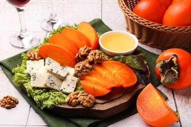 Photo of Delicious persimmon, blue cheese, nuts and honey served on tiled surface