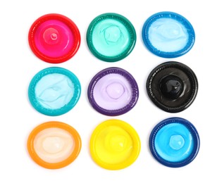 Unpacked colorful condoms on white background, top view. Safe sex