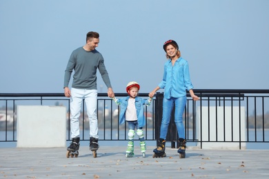 Happy family roller skating on embankment. Active leisure