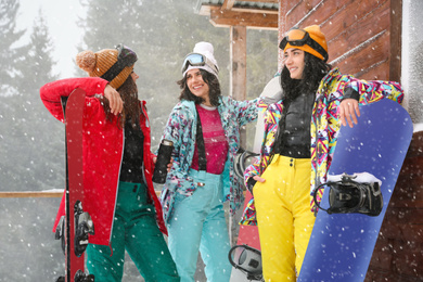 Friends with skis and snowboards wearing winter sport clothes outdoors