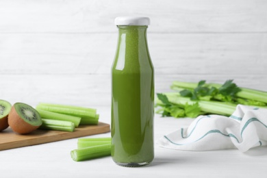 Photo of Bottle of fresh celery juice on white wooden table