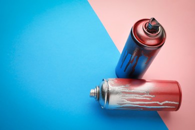 Photo of Used cans of spray paints on color background, space for text. Graffiti supplies
