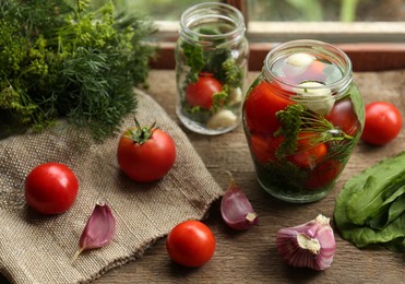 Photo of Glass jars, fresh vegetables and herbs on wooden table indoors. Pickling recipe