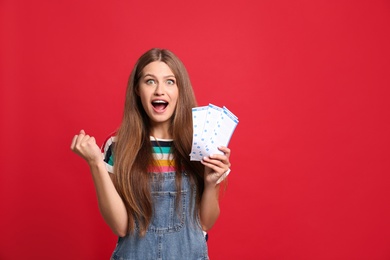 Portrait of emotional young woman with lottery tickets on red background