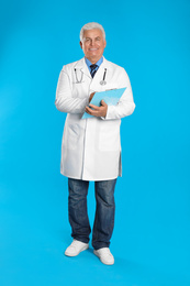 Senior doctor with clipboard on light blue background