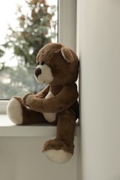Photo of Cute lonely teddy bear on windowsill indoors