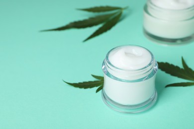 Glass jar of hemp cream on turquoise background, space for text. Natural cosmetics