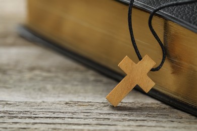 Christian cross and Bible on white wooden table, closeup