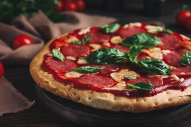 Photo of Pita pizza with pepperoni, cheese and basil on wooden table, closeup