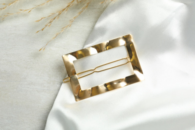 Beautiful gold hair clip on white table, top view