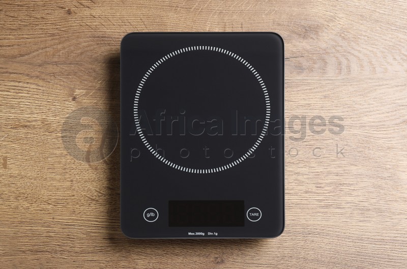 Modern digital kitchen scale on wooden table, top view