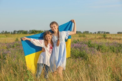 Happy girls with national flag of Ukraine in field