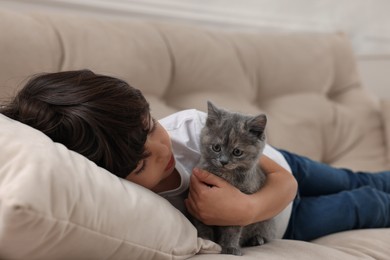 Photo of Cute little boy with kitten on sofa. Childhood pet
