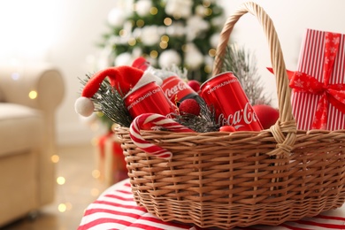 MYKOLAIV, UKRAINE - January 01, 2021: Basket with Coca-Cola drinks against blurred Christmas tree