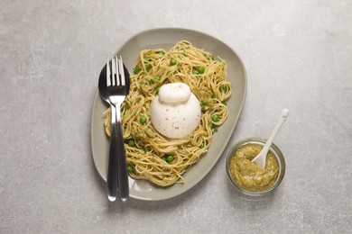 Photo of Delicious spaghetti with burrata cheese, peas and pesto sauce on light grey table, flat lay