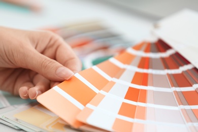 Woman with paint color palette samples at table, closeup