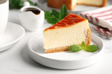 Photo of Piece of delicious caramel cheesecake served on white marble table, closeup