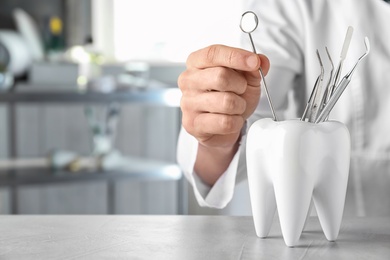 Dentist with professional tools at table in clinic, closeup. Space for text
