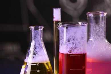 Photo of Laboratory glassware with colorful liquids on blurred background, closeup. Chemical reaction