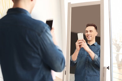 Young man taking selfie in front of mirror at home