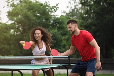 Friends playing ping pong outdoors on summer day