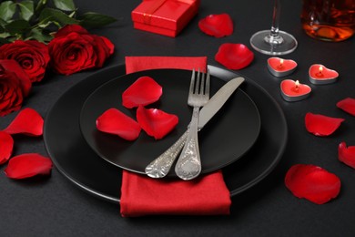 Photo of Beautiful table setting with burning candles and bouquet on black table for romantic dinner
