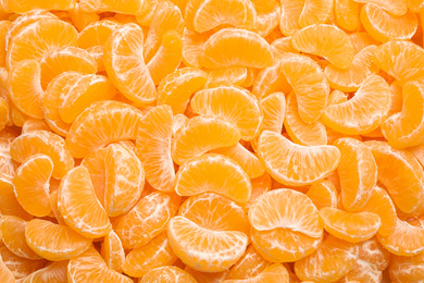 Photo of Fresh juicy tangerine segments as background, top view