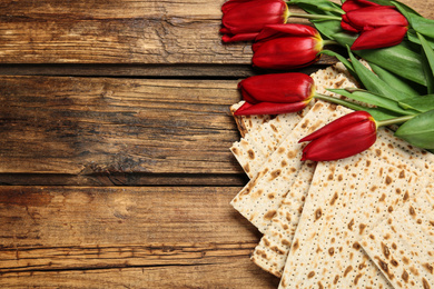 Tasty matzos and flowers on wooden table, flat lay with space for text. Passover (Pesach) Seder