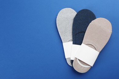 Soft cotton socks on blue background, flat lay. Space for text