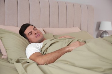 Man sleeping in comfortable bed with green linens