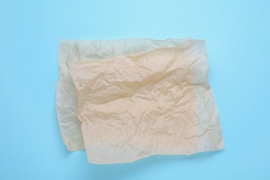Sheets of crumpled baking paper on light blue background, top view