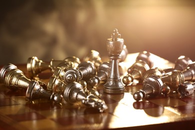 Chessboard with game pieces lit by lamp, closeup