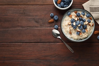 Tasty oatmeal porridge with blueberries and almond nuts served on wooden table, flat lay. Space for text