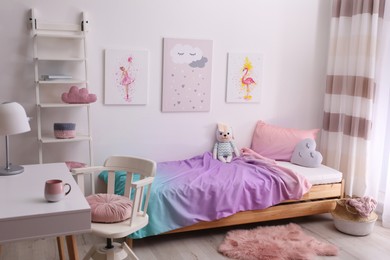 Comfortable bed with pink linens in children's room