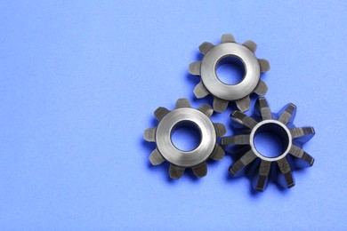 Photo of Different stainless steel gears on light blue background, flat lay. Space for text