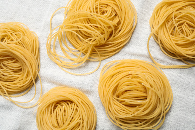 Capellini pasta on white tablecloth, flat lay