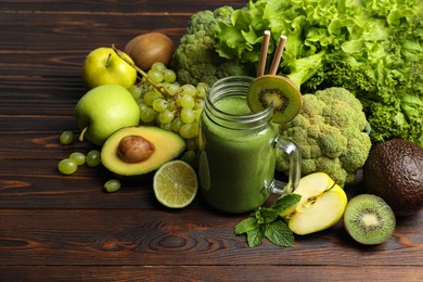 Green smoothie in mason jar and fresh ingredients on wooden table. Space for text