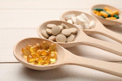 Photo of Spoons with different dietary supplements on white wooden table, closeup