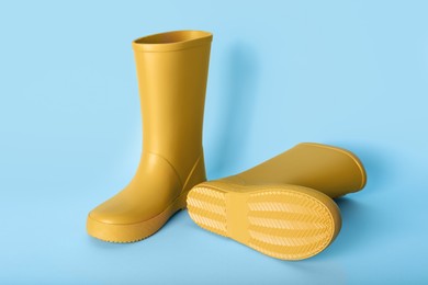 Pair of yellow rubber boots on light blue background